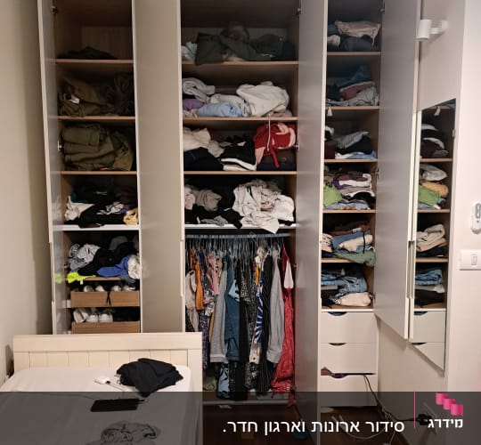 ארון בגדים פתוח עם בגדים מקופלים ותלויים